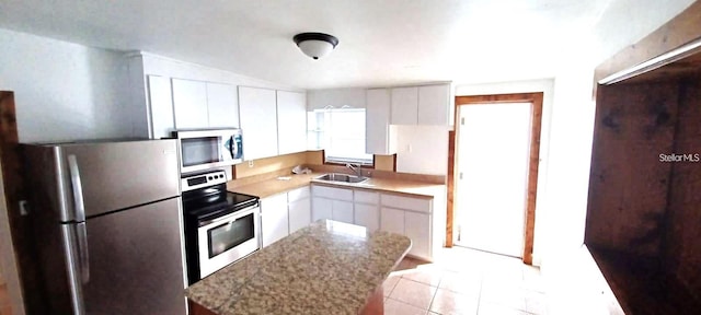 kitchen featuring appliances with stainless steel finishes, light stone counters, sink, light tile patterned floors, and white cabinetry