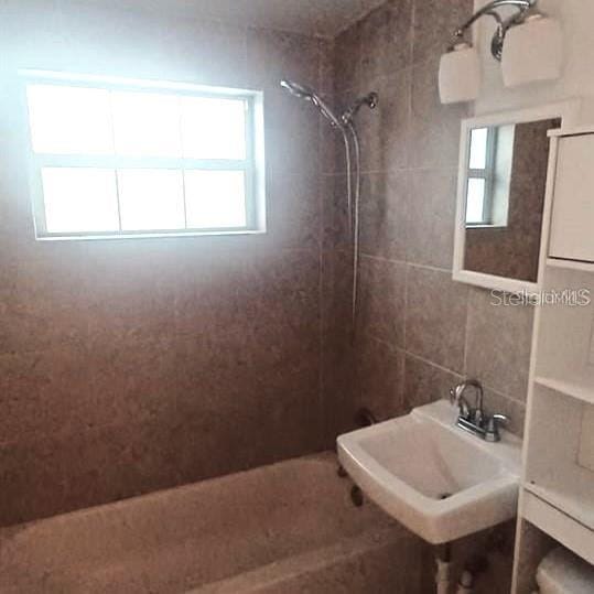 bathroom featuring a tile shower and sink