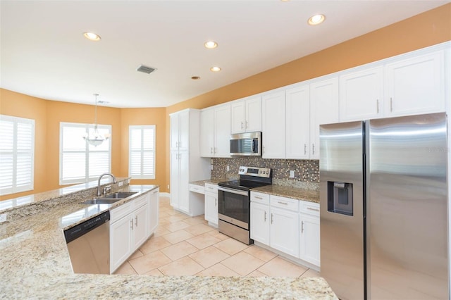 kitchen featuring sink, white cabinets, hanging light fixtures, and appliances with stainless steel finishes