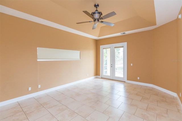 empty room featuring a raised ceiling, ceiling fan, french doors, and light tile patterned floors