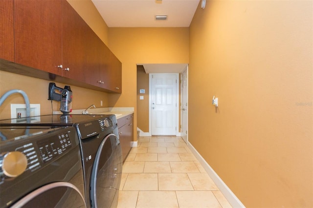 laundry area with cabinets, light tile patterned floors, and washing machine and clothes dryer