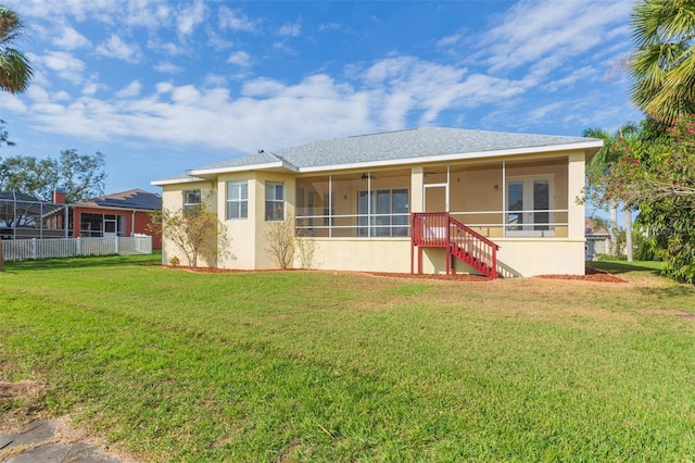 rear view of property featuring a lawn and a sunroom