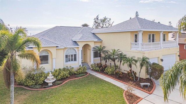 view of front of house featuring a garage, a balcony, and a front yard