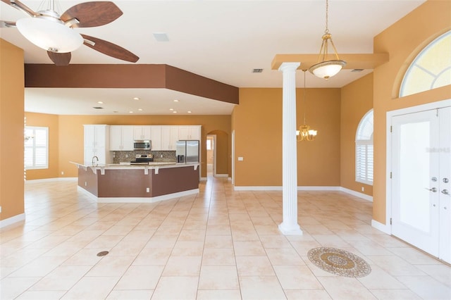 kitchen featuring backsplash, appliances with stainless steel finishes, decorative light fixtures, white cabinetry, and decorative columns