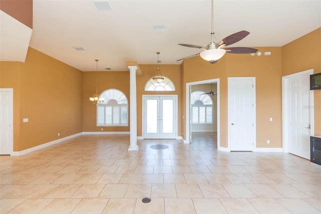 entryway with ceiling fan with notable chandelier, ornate columns, and light tile patterned floors