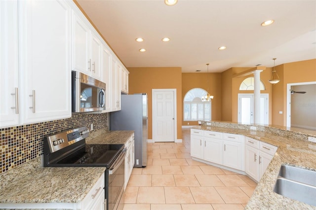 kitchen featuring hanging light fixtures, stainless steel appliances, an inviting chandelier, backsplash, and white cabinets