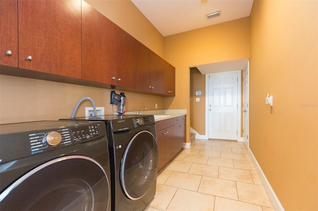 laundry area with cabinets, light tile patterned floors, washing machine and dryer, and sink