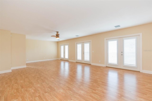 empty room featuring ceiling fan, french doors, and light hardwood / wood-style flooring