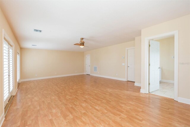 empty room with ceiling fan, a wealth of natural light, and light hardwood / wood-style flooring