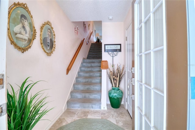 stairs featuring a textured ceiling