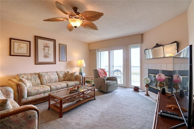 carpeted living room featuring ceiling fan, a fireplace, and a textured ceiling