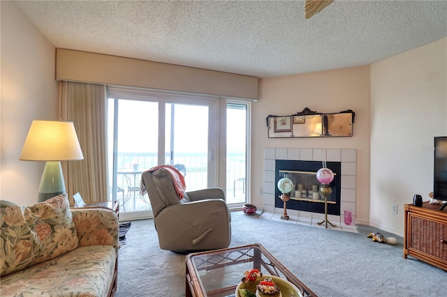 carpeted living room featuring a tiled fireplace and a textured ceiling