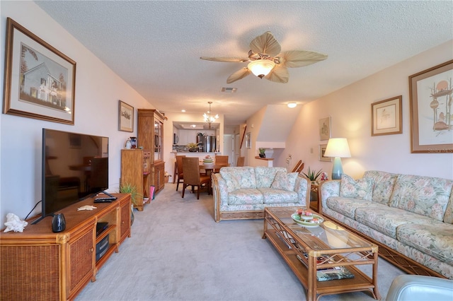 living room featuring a textured ceiling, ceiling fan with notable chandelier, and light carpet