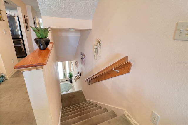 staircase featuring a textured ceiling