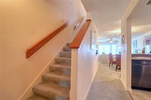 staircase featuring ceiling fan, carpet, and a textured ceiling