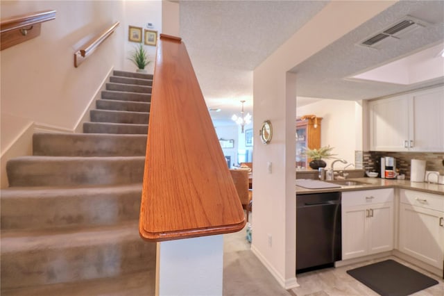 stairs with a textured ceiling, a notable chandelier, and sink