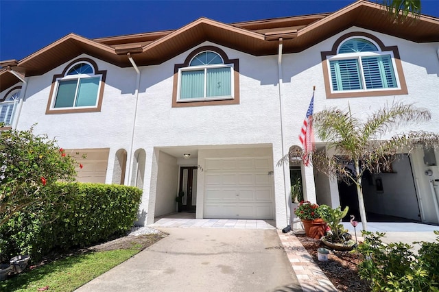 townhome / multi-family property with a garage, driveway, and stucco siding