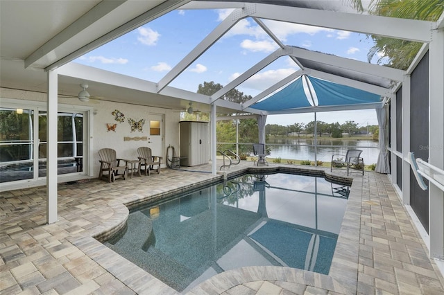 view of pool with a water view, glass enclosure, and a patio