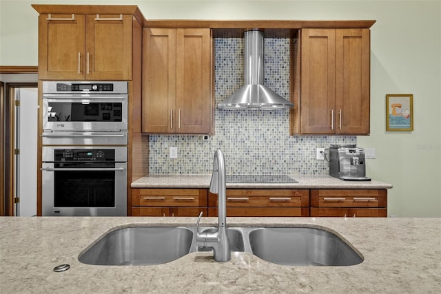 kitchen with tasteful backsplash, double oven, sink, and wall chimney exhaust hood