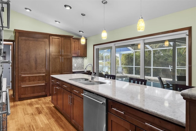 kitchen featuring sink, hanging light fixtures, light stone countertops, vaulted ceiling, and stainless steel dishwasher