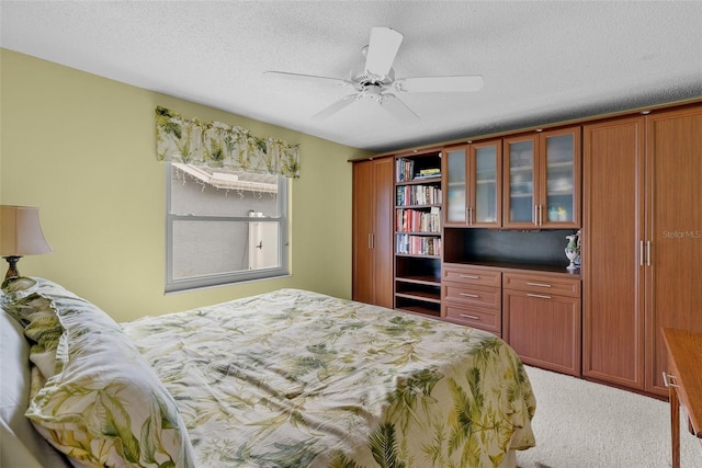 carpeted bedroom with ceiling fan and a textured ceiling