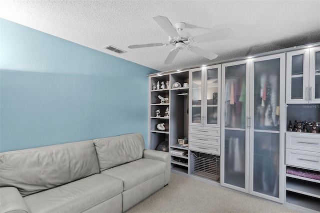 carpeted living room featuring ceiling fan and a textured ceiling