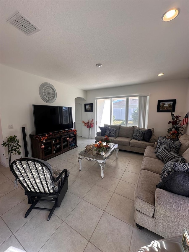 living area with arched walkways, recessed lighting, visible vents, light tile patterned flooring, and a textured ceiling