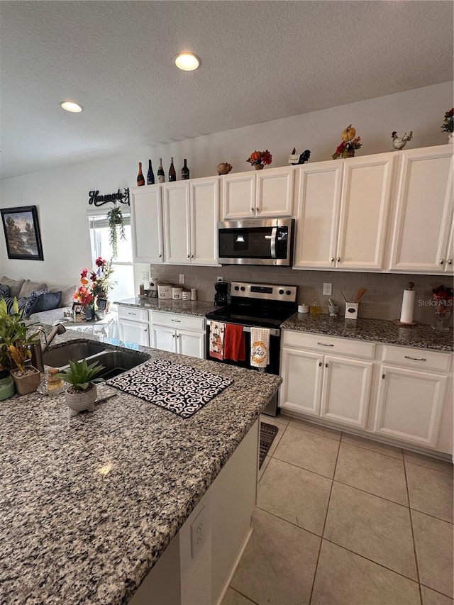 kitchen with light tile patterned floors, stainless steel appliances, white cabinetry, and sink