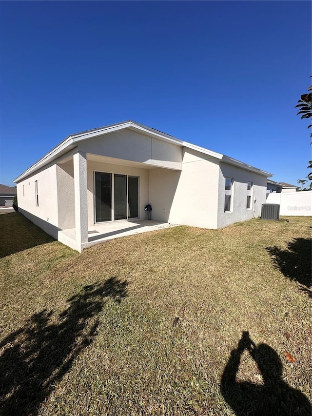 rear view of house with stucco siding, a yard, fence, and a patio