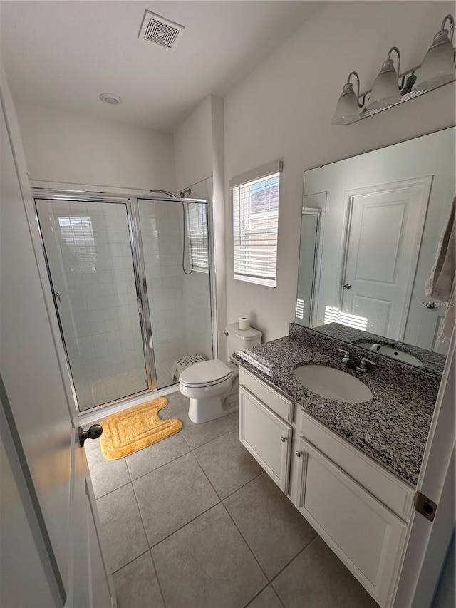 bathroom with toilet, vanity, tile patterned floors, and a shower with shower door