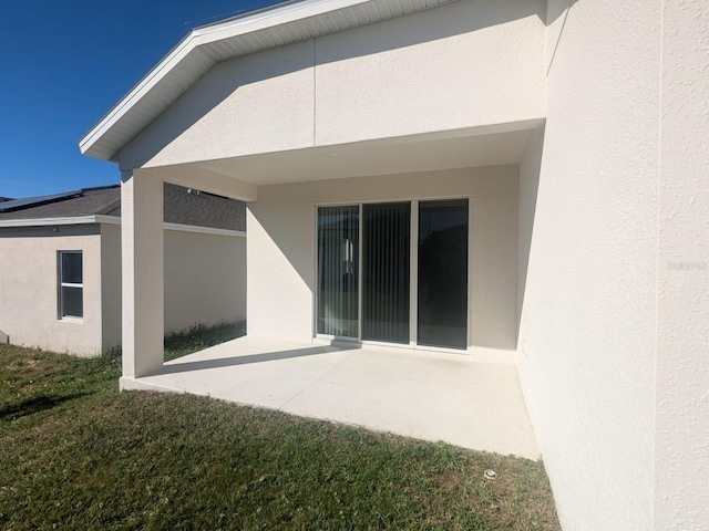 back of house featuring a patio area, a lawn, and stucco siding