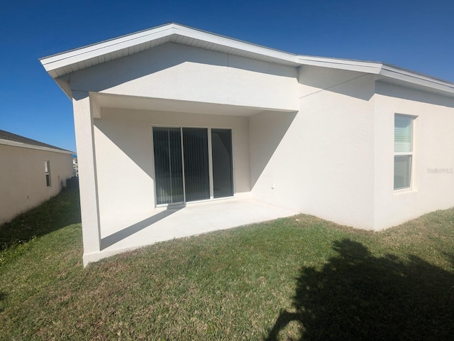 rear view of house with a lawn and stucco siding