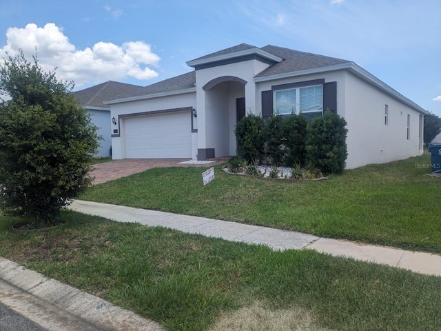 view of front of house featuring driveway, a front lawn, an attached garage, and stucco siding