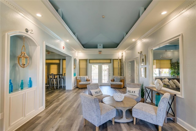 sitting room with ornamental molding, a raised ceiling, wood finished floors, and french doors