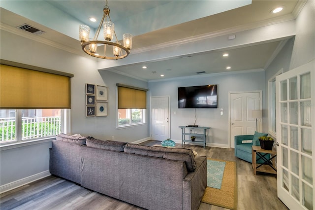 living room featuring baseboards, visible vents, ornamental molding, wood finished floors, and a chandelier