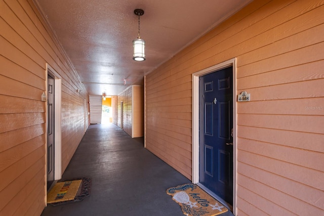 hallway featuring a textured ceiling and wooden walls