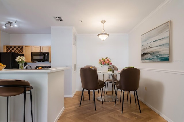 kitchen with decorative light fixtures, light countertops, crown molding, light brown cabinetry, and black appliances