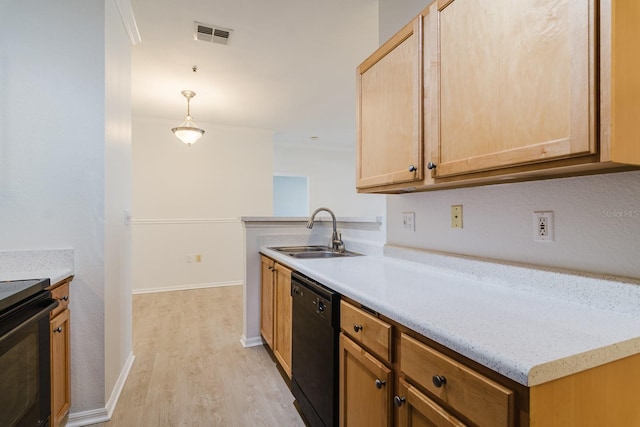 kitchen featuring light countertops, hanging light fixtures, light wood-style flooring, a sink, and black appliances