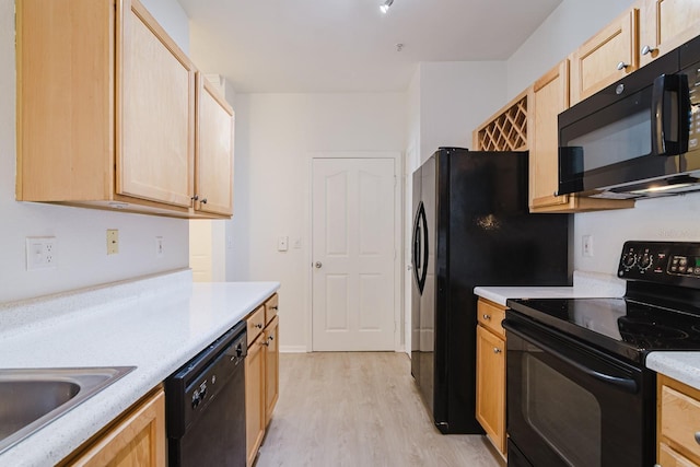 kitchen with black appliances, light brown cabinets, light countertops, and light wood finished floors