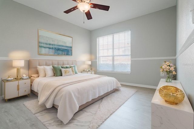 bedroom with light wood-type flooring, ceiling fan, and baseboards