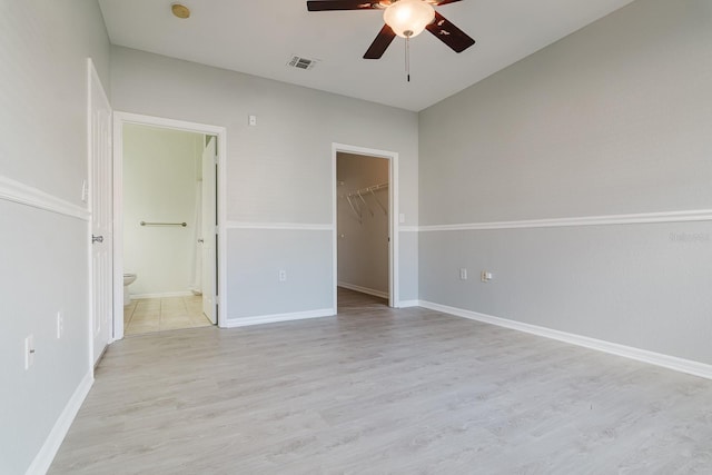 unfurnished bedroom featuring baseboards, visible vents, a spacious closet, and light wood finished floors