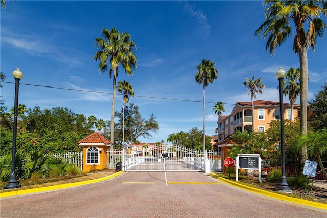 view of street featuring a gate, curbs, a gated entry, and street lights