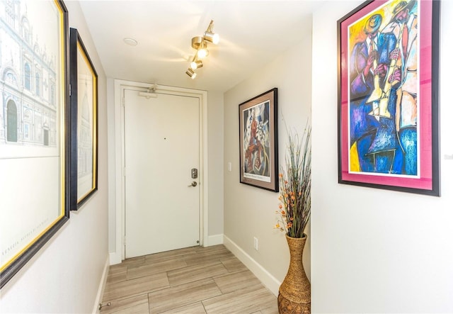 doorway to outside with rail lighting and light hardwood / wood-style floors