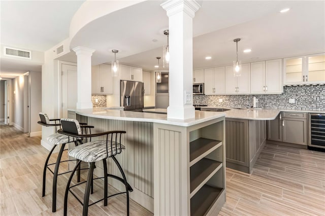 kitchen with appliances with stainless steel finishes, gray cabinets, kitchen peninsula, beverage cooler, and white cabinets