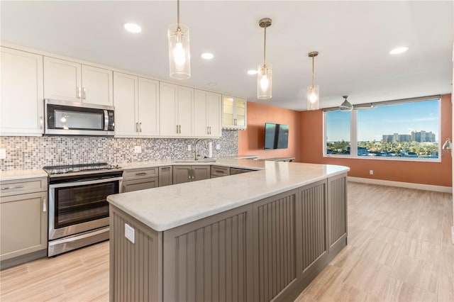 kitchen with sink, gray cabinets, stainless steel appliances, decorative light fixtures, and kitchen peninsula