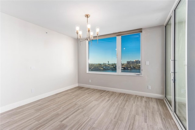 unfurnished room with a water view, light wood-type flooring, and a notable chandelier