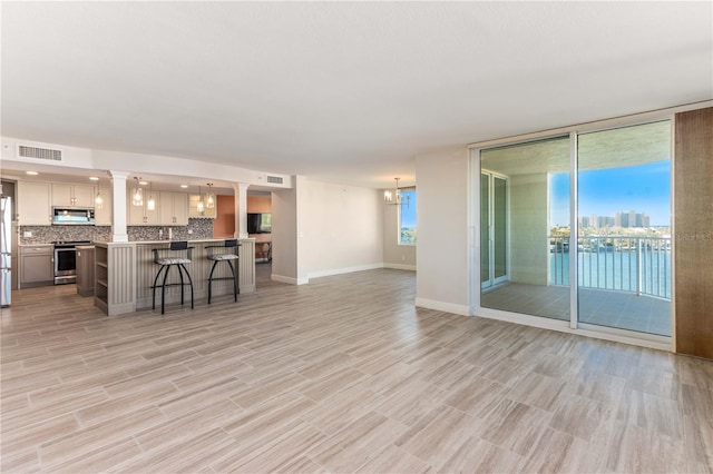 736 Island Way Unit 606, Clearwater Beach, FL 33767 - kitchen with appliances with stainless steel finishes, open floor plan, a kitchen breakfast bar, backsplash, and light countertops