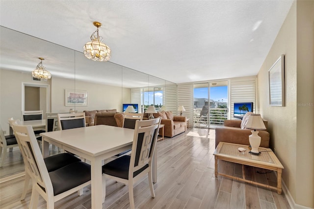 dining room featuring a chandelier, a textured ceiling, light wood-type flooring, and floor to ceiling windows