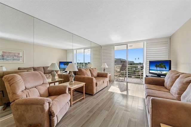 living room featuring expansive windows, light hardwood / wood-style floors, and a textured ceiling