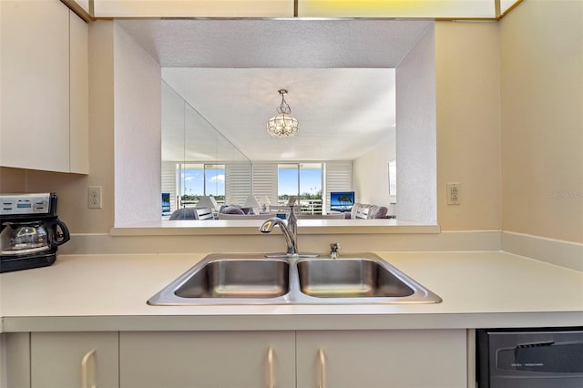 kitchen featuring dishwasher, sink, and a chandelier